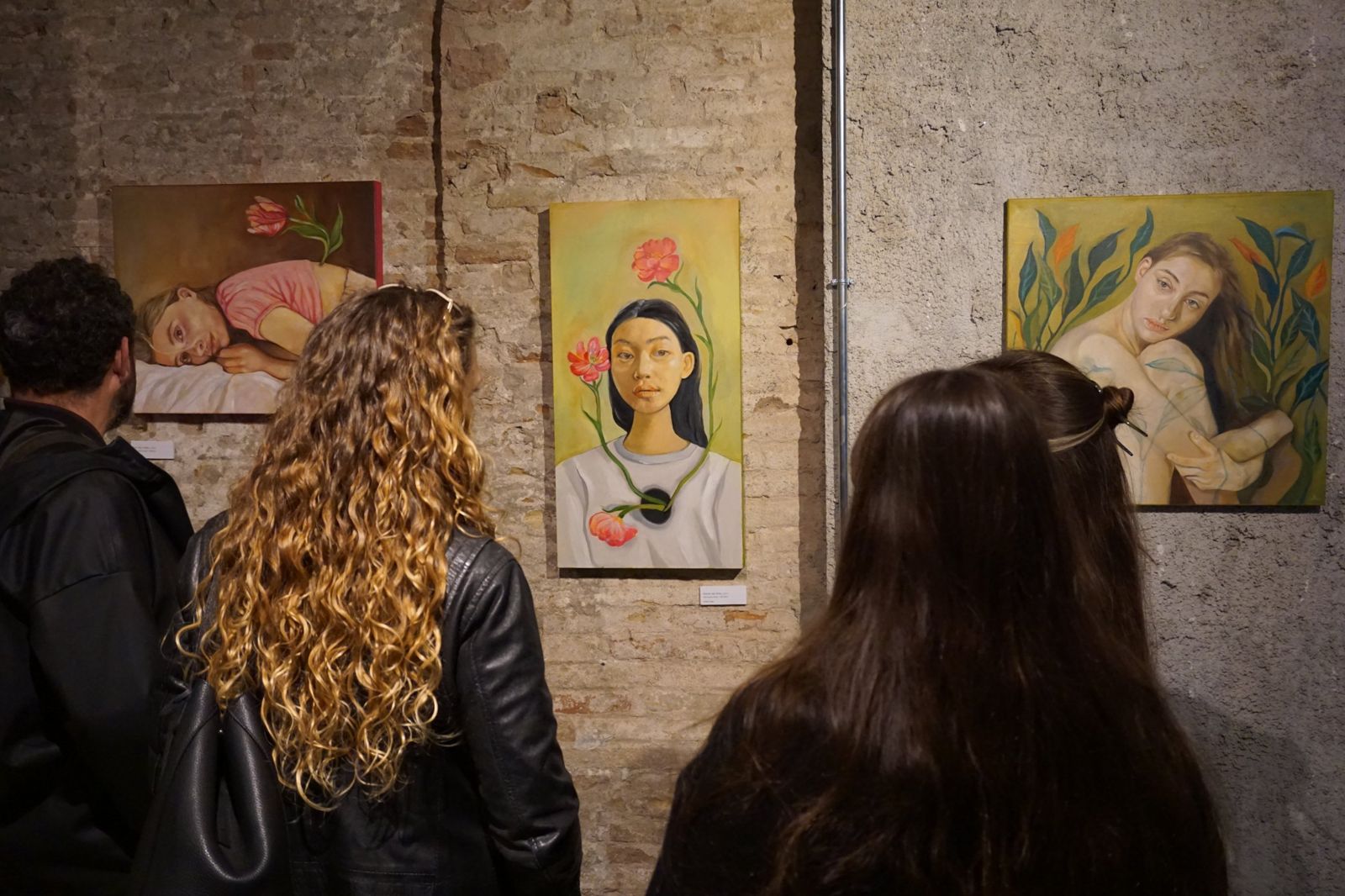 Público contemplando retratos pintados al óleo con flores en una exposición temporal